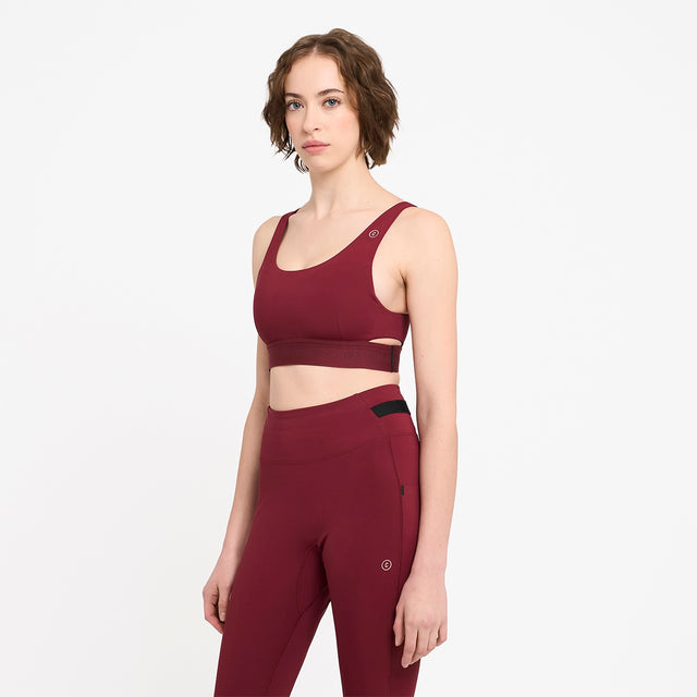 Woman wearing a Ciele Athletics Women's QCKBra Sports Bra in Crimson Red Maroon sports bra and leggings on a white background