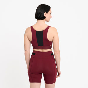 Woman wearing a Ciele Athletics Women's QCKBra Sports Bra in Crimson Red Maroon sports bra with black accents on a white background
