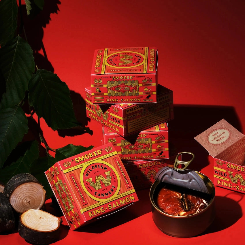 Wildfish Cannery Smoked King Salmon on a red background with a metal container of salmon.