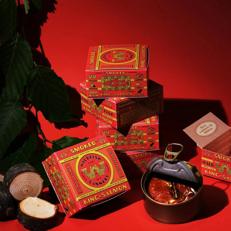 Wildfish Cannery Smoked King Salmon on a red background with a metal container of salmon.