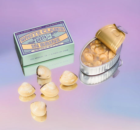 Siesta Co. White Clams in Brine with shell-shaped objects and packaging on a gradient background