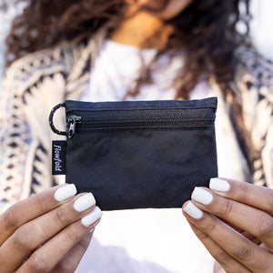 Flowfold Essentialist Mini Zip Pouch in black being held by a person.