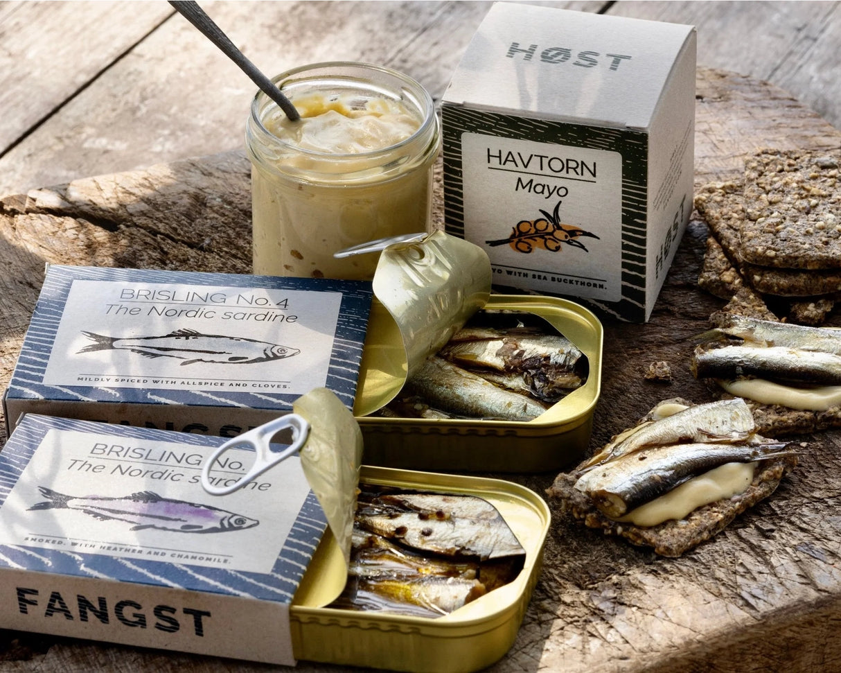 Fangst Nordic Smoked Sardine with Heather & Chamomile in tins and a jar of mayonnaise on a wooden surface.