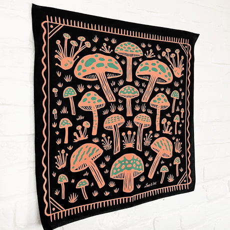 Land & She Field of Mushrooms Bandana on a neutral brick background at an angle.