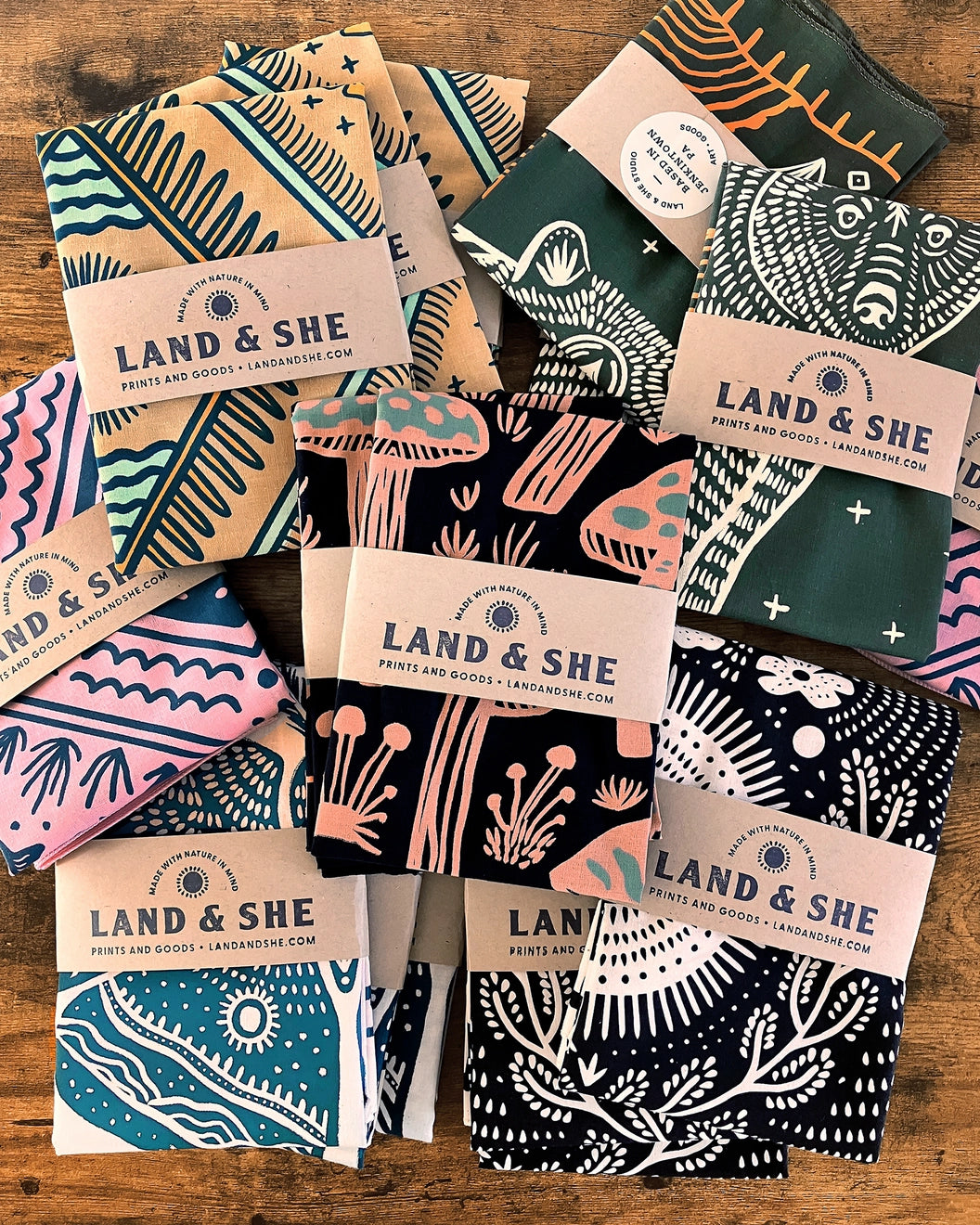 Land & She Field of Mushrooms Bandana packaged on a wood background with other bandanas.