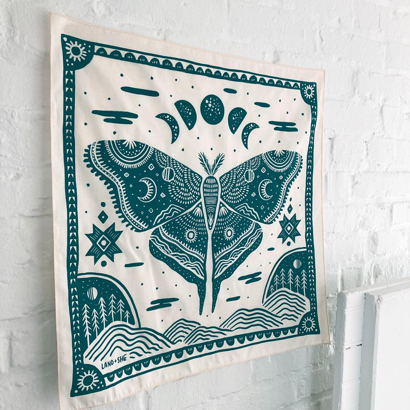 Land & She Luna Moth Bandana on a neutral brick background at an angle.