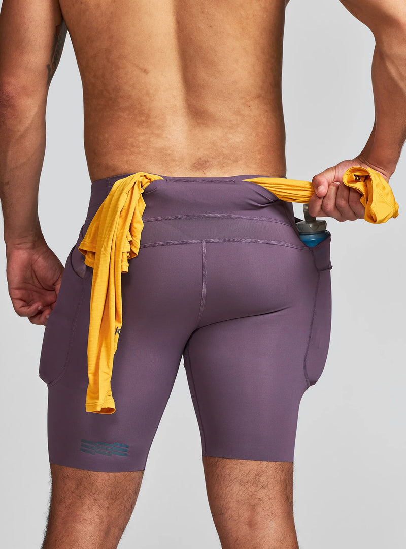 Janji Men's 8" Trail Half Tight in Massif worn by a man from the rear on a neutral background.