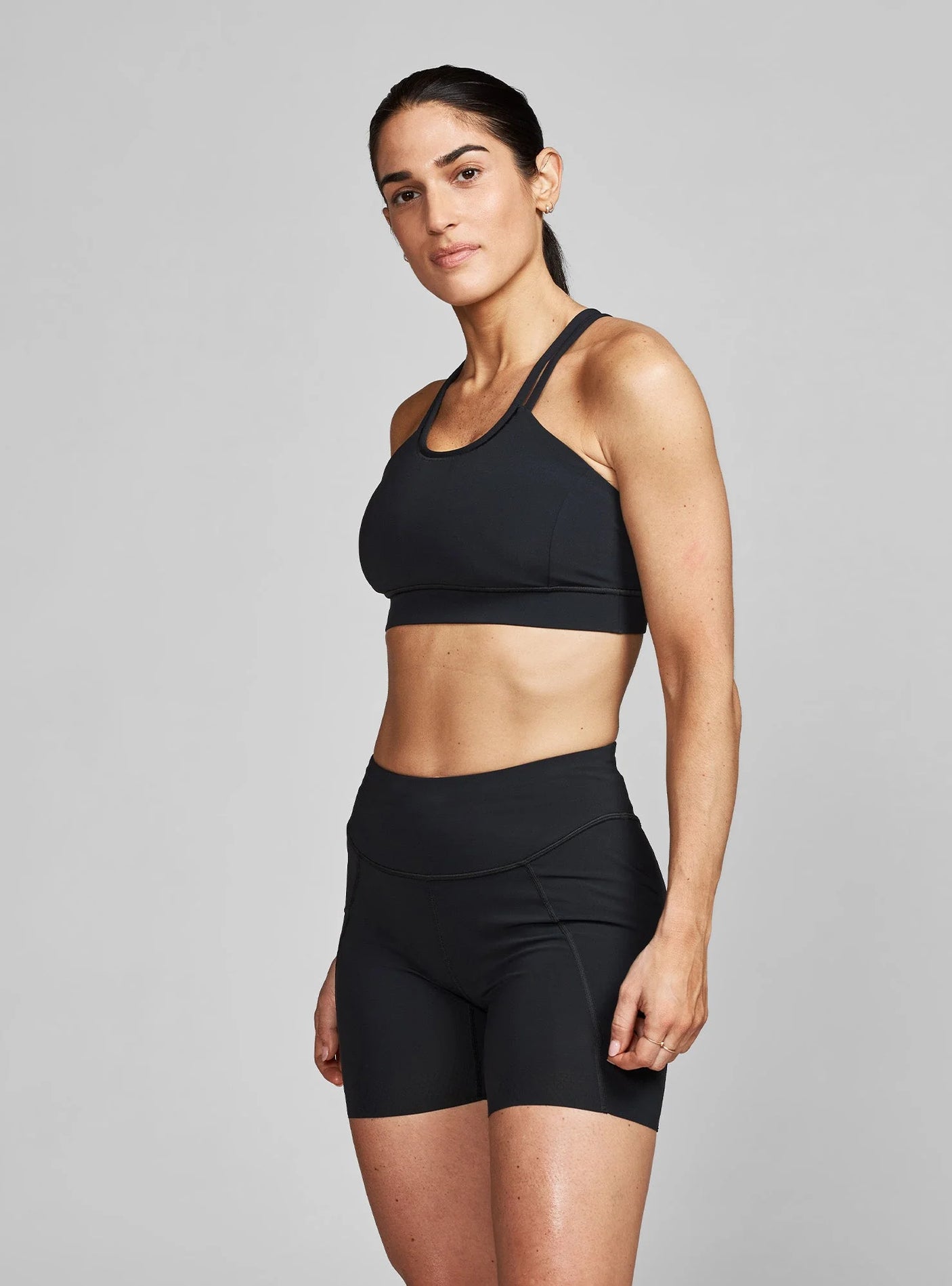 Janji W's Pace Sports Bra in Midnight being worn by a woman on a neutral background.