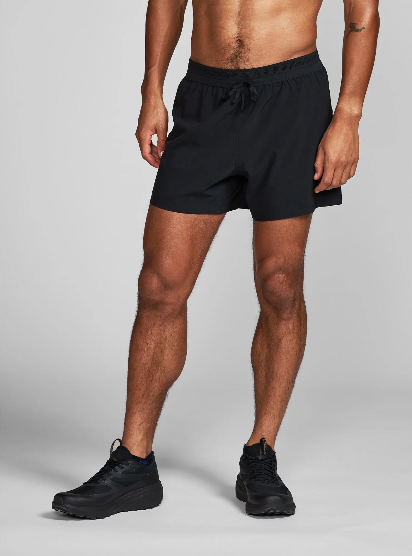 Janji's M's 5" AFO Middle Short in Midnight on a neutral background worn by a man.