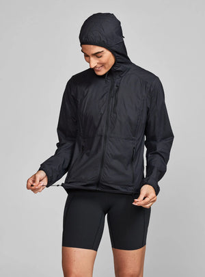 Janji W's Zephyrunner Wind Shell in Midnight being worn by a woman on a neutral background.