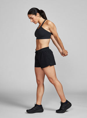 Janji's Women's 3" AFO Middle Short in Midnight being worn by a woman from the side.