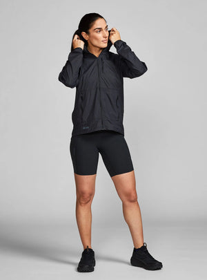 Janji W's Zephyrunner Wind Shell in Midnight being worn by a woman from the front on a neutral background.