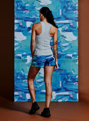 Janji's Women's 3" AFO Middle Short in Sea Sky Cloud from the rear being worn by a woman.