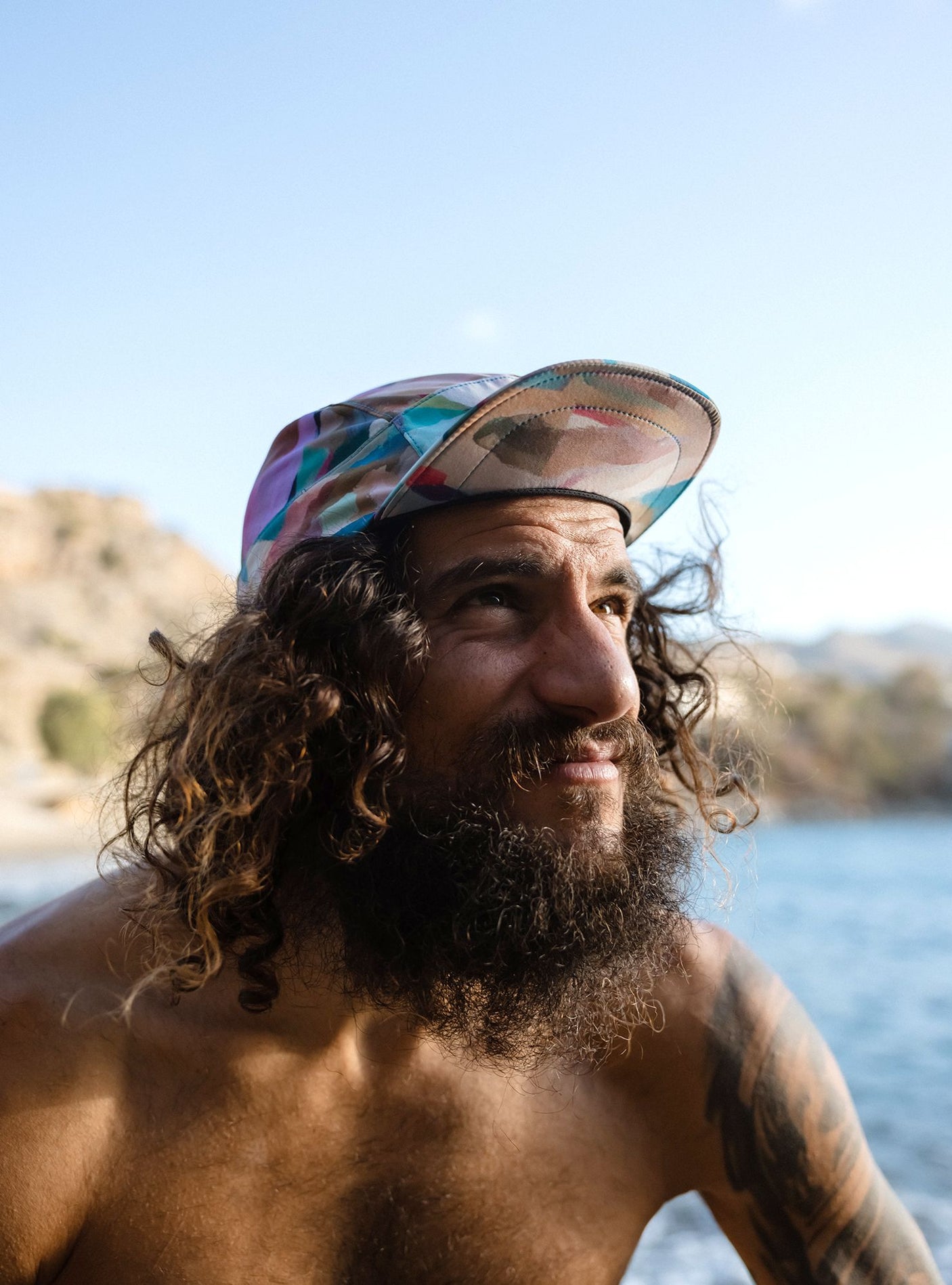 Janji AFO Hyperlight Cap worn by a man outdoors near the water.