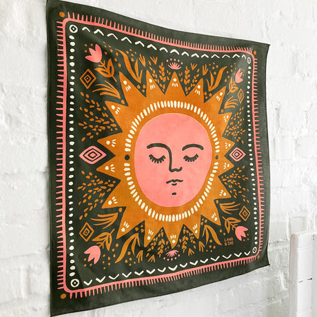 Land & She Sun Still Rises Bandana on a neutral brick background at an angle.