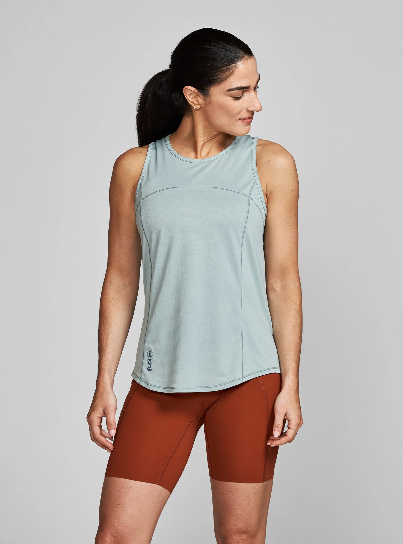 Janji W's Run All Day Tank on a neutral background being worn by a woman.