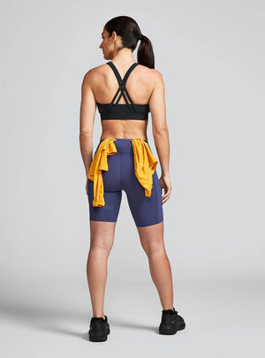 Janji's Women's 7" Pace Short in Thunderstorm being worn by a woman from the rear on a neutral background.