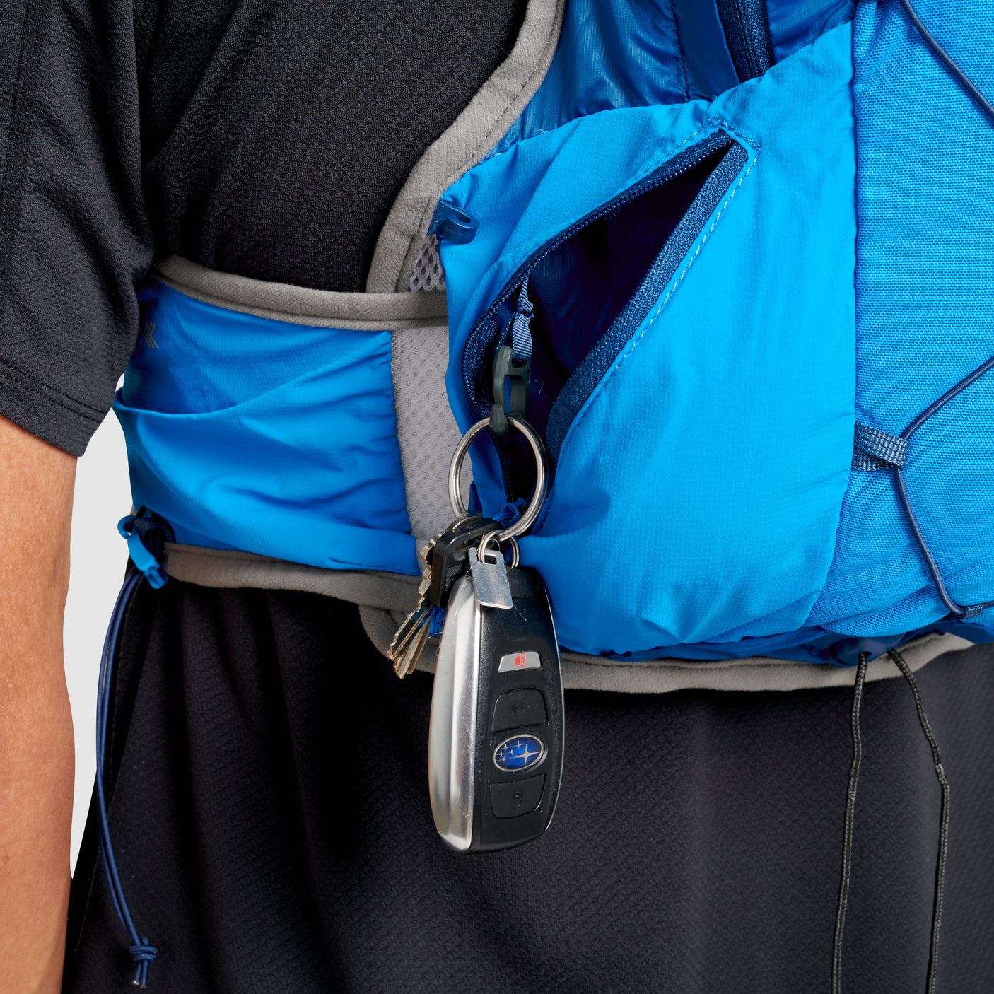 The Ultimate Direction Ultra Vest 6.0 on a neutral background with a closeup of the key pocket.