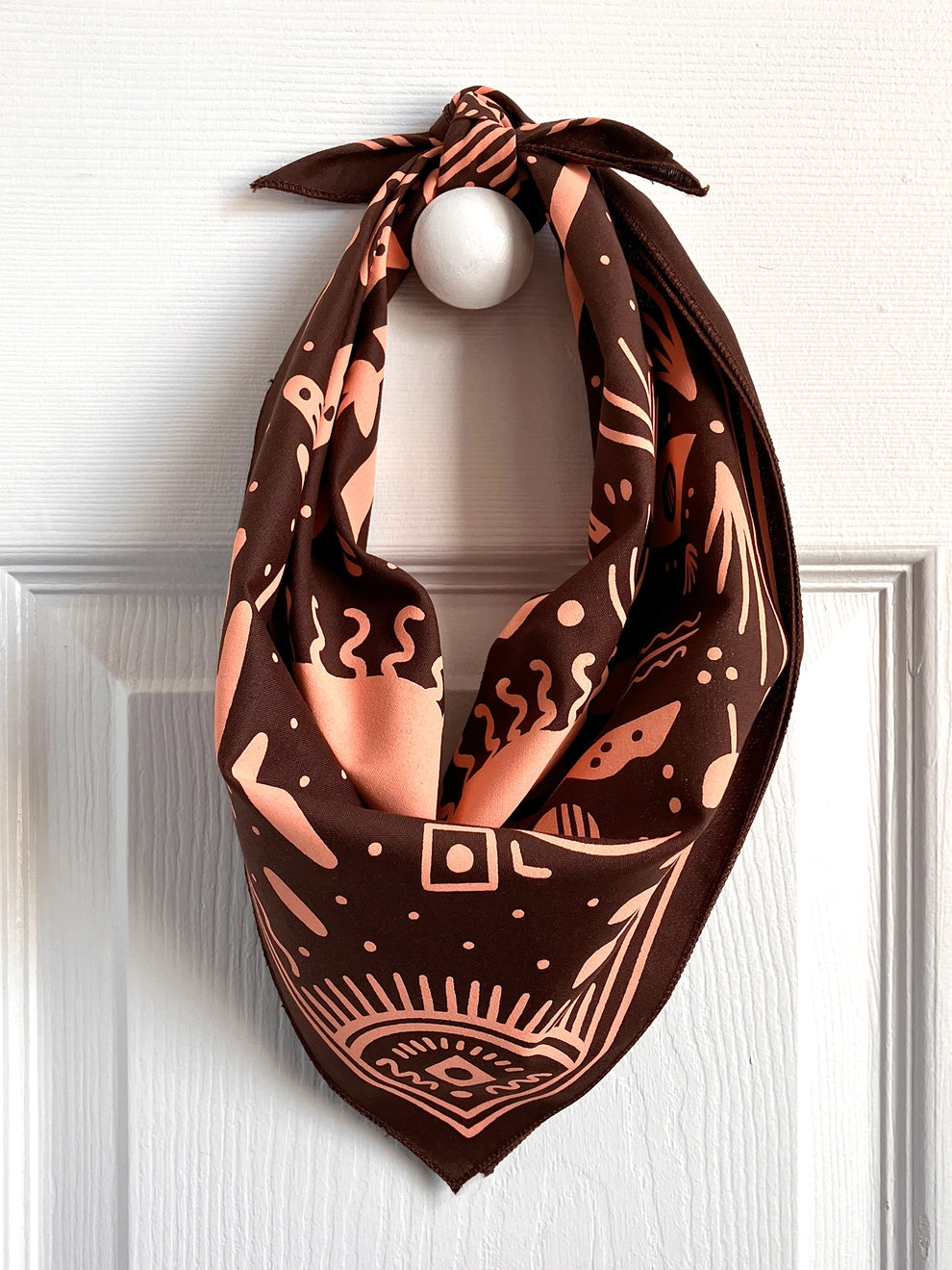 Land & She Western Sun Bandana tied and hung from a hat rack.